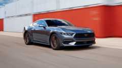 2024 Ford Mustang GT driving past stacked containers