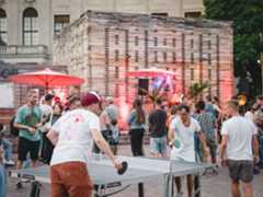 Tischtennis am Co-Labor Zwei Menschen spielen Tischtennis, im Hintergrund sind Gäste einer Veranstaltung vor dem Co-Labor zu sehen