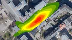 Abbildung - Modellierung der Luftschadstoffbelastung Luftaufnahme einer Straße mit eingezeichneter Ellipse, die farblich von rot (in der Mitte) über orange und gelb in grün übergeht