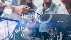 Themenbild Wirtschaft: Zahlen, Daten, Fakten Eine Gruppe Menschen sitzt in Arbeitsatmosphäre um einen Laptop.