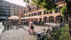 Leipziger Naschmarkt mit einem Straßencafé, Läden und dem Alten Leipziger Rathaus im Hintergrund