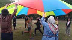 KuGeL Lotsinnen mit Schwungtuch Mehrere Menschen halten ein buntes Schwungtuch in die Höhe, zwei rennen untendrunter durch