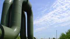 Wärmeversorgung über Fernwärme Fernwärmerohre im Vordergrund und ein Heizkraftwerk im Hintergrund