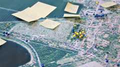 Ortschaftsstrategien der Stadt Leipzig Auf einem Luftbild wurden mit gelben und blauen Pins Orte markiert. Daneben kleben Zettel mit weiteren Informationen, die nicht genau zu lesen sind.