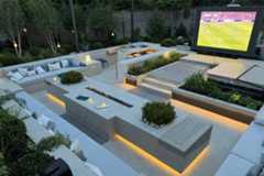 Stunning outdoor cinema area with built in sofas surrounding using astor grey porcelain paving, hot tub in the background.***Designed by Designscape | Built by Landscapes By Design
