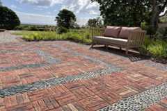 2-seater outdoor sofa at edge of rectilinear area paved with Old English Belgian bricks laid basketweave with pebble detailing.***Hal Forbes Adam, www.halforbesadam.com