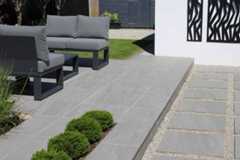 Staggered slabs in between pebbles lead to long step up to patio of kandla grey porcelain paving with modern outdoor furniture.***Oakleigh Manor, www.oakleighmanor.com