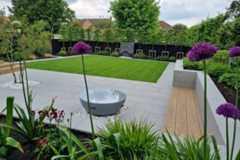 Square lawn sits in the middle of polished concrete porcelain patio with black slate water feature, flowerbeds surround.***Andrew Jordan Landscape & Garden Design