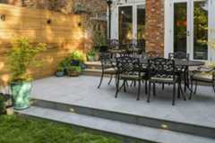 French doors overlook patio of Florence storm porcelain outdoor tiles uk, with 2 steps down to lawn. Design by Jaki Grosvenor. ***Design by JakiGrosvenor.com | Built by Acacia-gardens.co.uk | Photos by Anna Omiotek-Tott, annatott.com