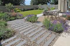 Views with lavender in the foreground and composite battens in the distance shows steel grey porcelain planks with inset pebbles.***Outerspace Creative Landscaping
