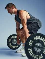 Mees tõstab kangi jõusaalis, kandes sportlikku riietust.