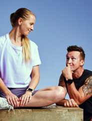 Naistreener ja mees klient istuvad ning arutavad treeningplaani.