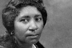 Portrait of Carrie William Hall wearing a fur over her clothes. She wears earrings, a large broach, and a necklace.