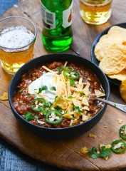 Chili in bowl with beer and tortilla chips.