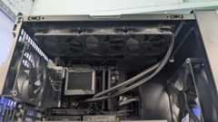 A inside view of the HAVN BF 360 case with the top taken off and a radiator installed for the AIO cooler. With the inside built wihth PC components, standing on a white desk with a background of PC component boxes on a bookshelf.