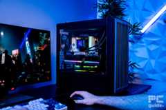 The HAVN BF 360 Flow case build sitting on a table showing its components. Next to it is a mouse, keyboard, and monitor with someones arm on the mouse playing Cyberpunk 2077 on the monitor.