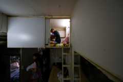 「棺桶ハウス」の上層ユニットで休む住民。2024年8月15日撮影(2025年 ロイター/Tyrone Siu)