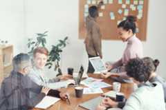 Personas trabajando en equipo junto a mesa llena de papeles.