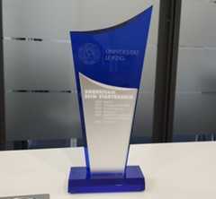 Auf den uniinternen Wanderpokal wurde zum zweiten Mal "Dezernat 2" eingraviert. Foto: Ulf Walther Der Pokal ist hochkantig und besteht aus blauem Acryl-Glas, in der Mitte sind auf einer grauen Metallfläche die Gewinnerteams der vergangenen Jahre eingraviert.