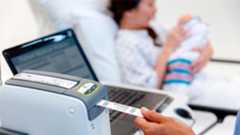 Health professional using a Zebra desktop printer to label a patient wristband. Health professional using a Zebra desktop printer to label a patient wristband.